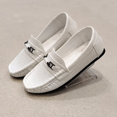 White loafers with black accents on a beige background