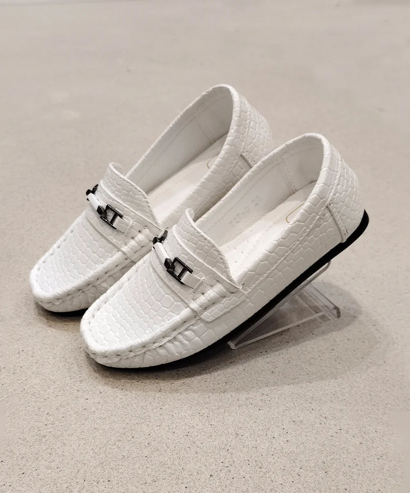 White loafers with black accents on a beige background