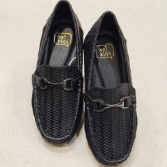 Pair of black woven shoes with a gold logo on a beige background