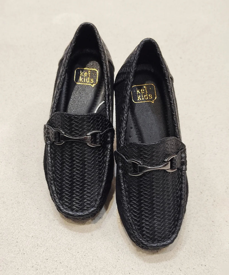 Pair of black woven shoes with a gold logo on a beige background