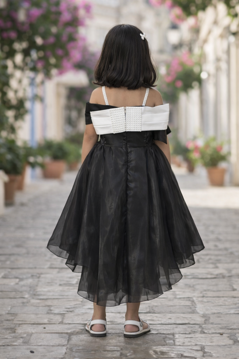 Woman wearing a black and white dress walking on a street with flowers and buildings in the background