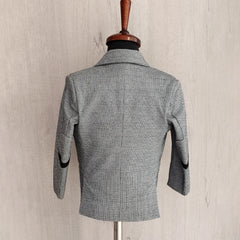 Gray checkered blazer on a mannequin against a beige wall.