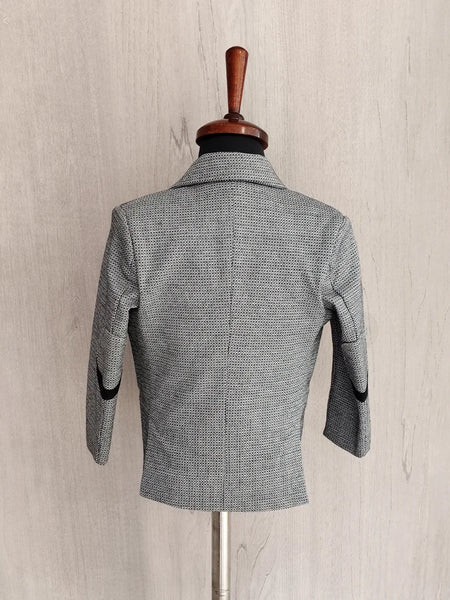 Gray checkered blazer on a mannequin against a beige wall.