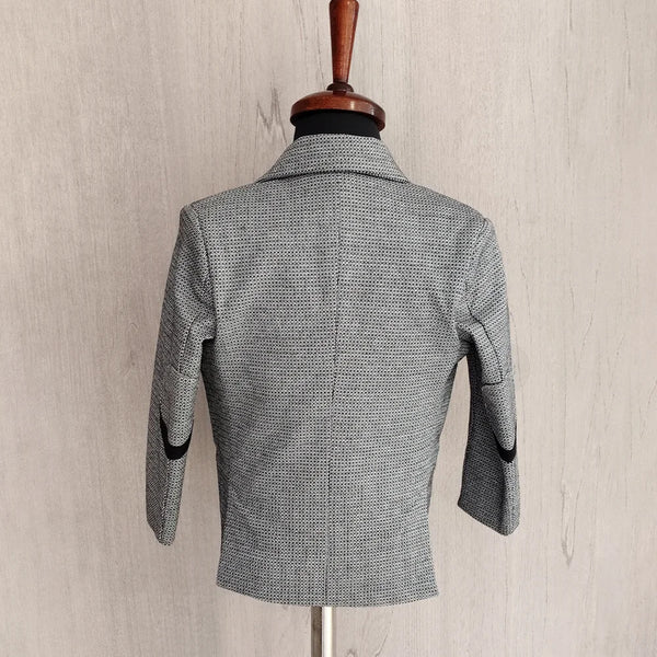 Gray checkered blazer on a mannequin against a beige wall.