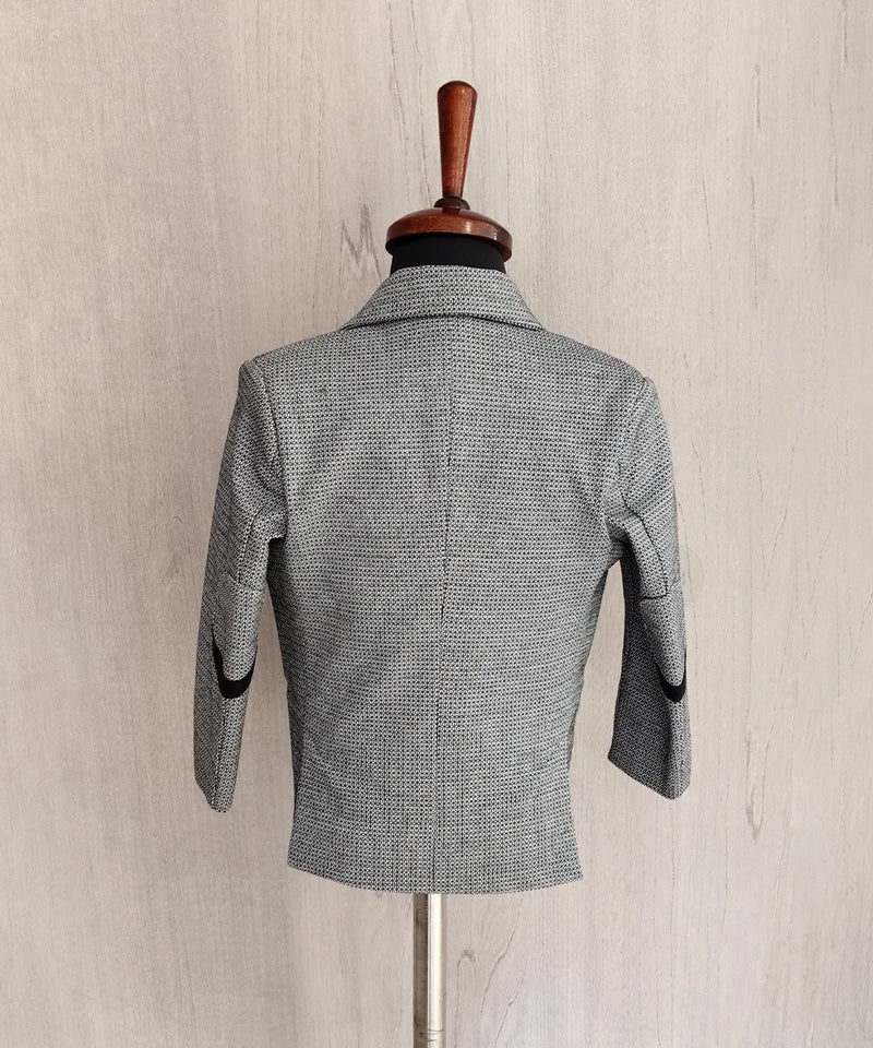 Gray checkered blazer on a mannequin against a beige wall.