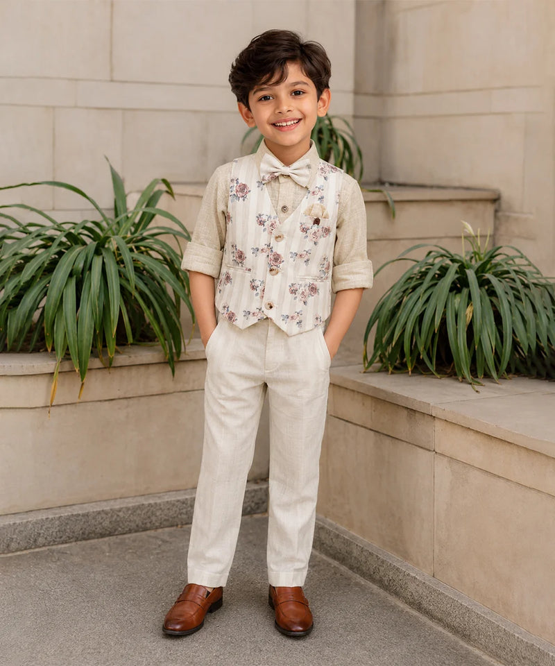 Young boy in formal attire standing outdoors with plants in the background