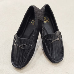 Pair of black woven loafers on a light beige background
