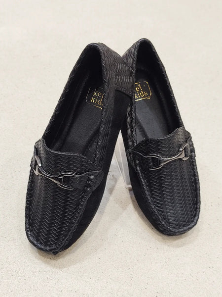 Pair of black woven loafers on a light beige background