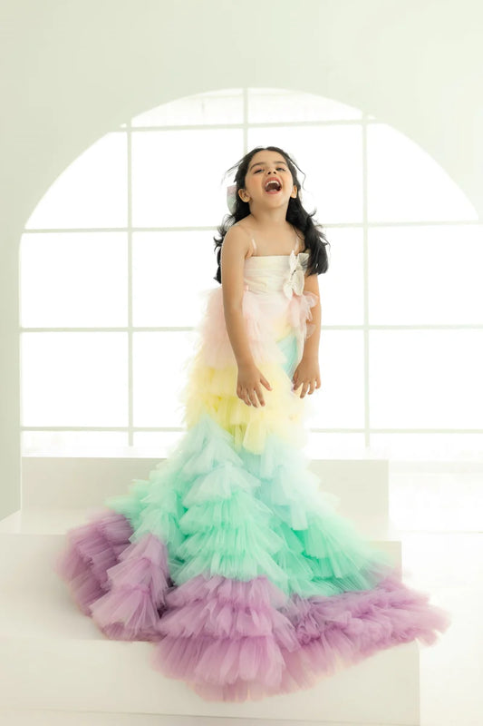 It’s a multi coloured two-in-one fancy ruffle gown for girl that features a beautiful bow making it a perfect birthday dress.