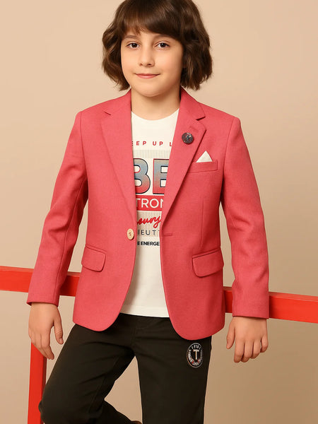 Child wearing a red blazer over a white shirt with text, standing against a beige background.