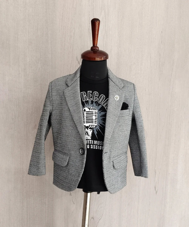 Gray blazer over a black t-shirt with graphic design on a mannequin against a beige wall.