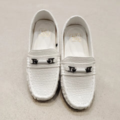 Pair of white loafers with metal buckles on a light gray background