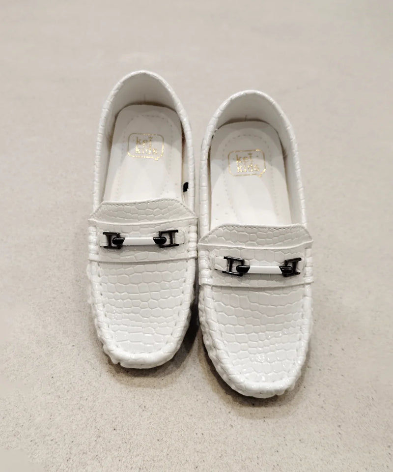 Pair of white loafers with metal buckles on a light gray background