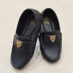 Black loafers with gold accents on a light beige background