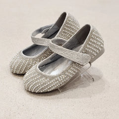 Pair of silver embellished shoes on a light beige background