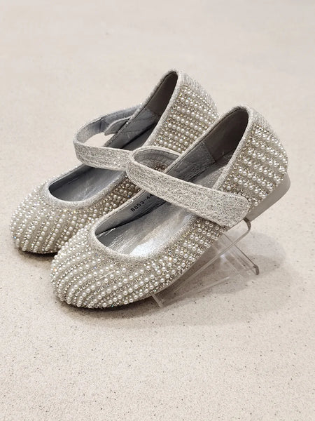 Pair of silver embellished shoes on a light beige background