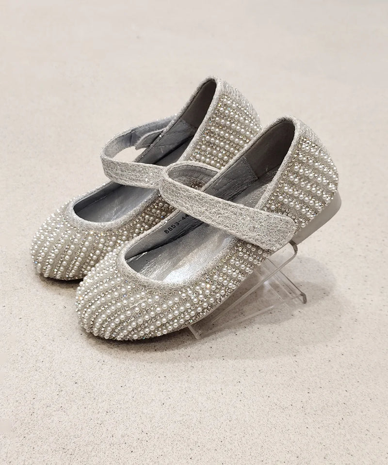 Pair of silver embellished shoes on a light beige background