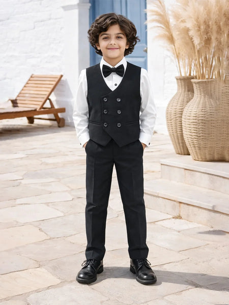 boy in a formal black suit with a bow tie standing outdoors.