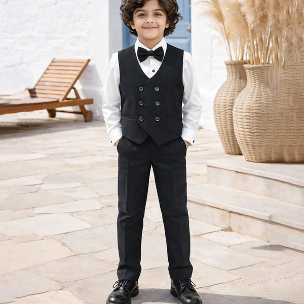 boy in a formal black suit with a bow tie standing outdoors.
