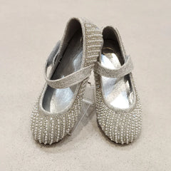 Pair of silver beaded shoes on a beige background