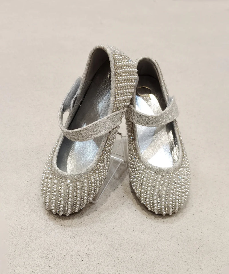 Pair of silver beaded shoes on a beige background