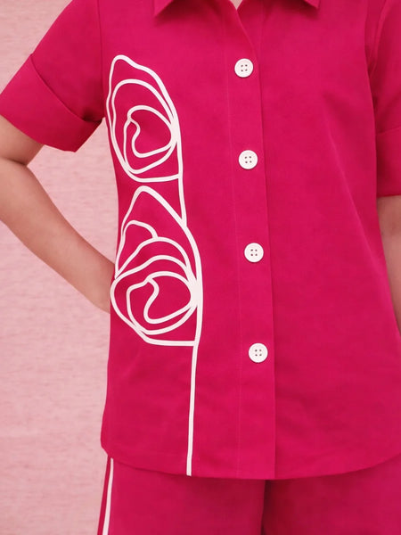 Pink shirt with white floral design on a pink background