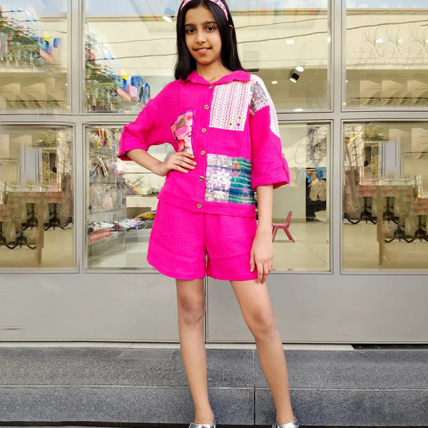 Young girl in a bright pink outfit standing in front of a store window.
