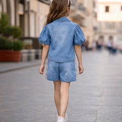 Child wearing a denim outfit walking on a city street.
