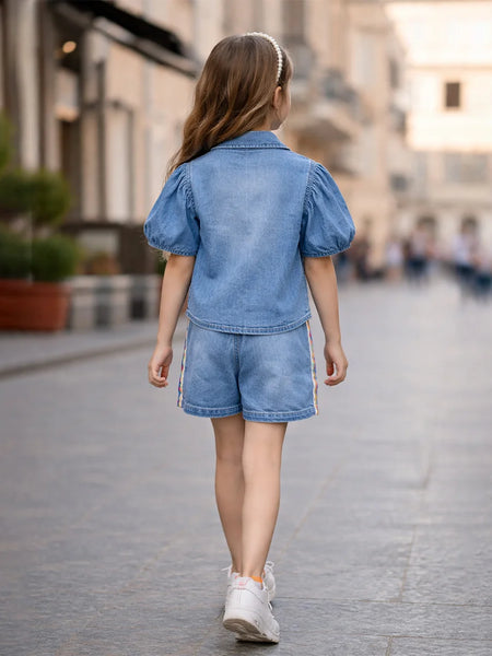 Child wearing a denim outfit walking on a city street.