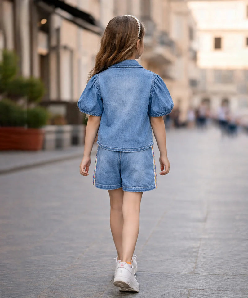 Child wearing a denim outfit walking on a city street.