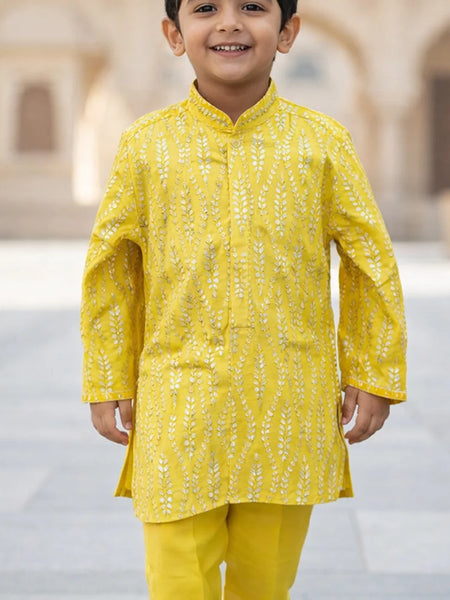 Child wearing a yellow traditional outfit with a blurred architectural background