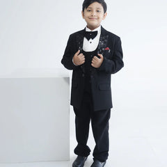 This boys wedding outfit consists of a black Colored coat, waistcoat, matching pants and a self-textured white shirt. It features a matching bow, a broach, a pocket square and beautiful work detailing on the collar that uplifts the entire look.