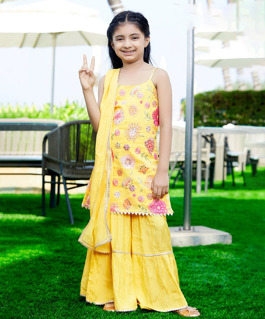 This kids party wear consists of a yellow coloured stylish kurta, a dupatta and a sharara perfect for a haldi ceremony look. It features tassel on the side of kurta and lace detailing on the dress.