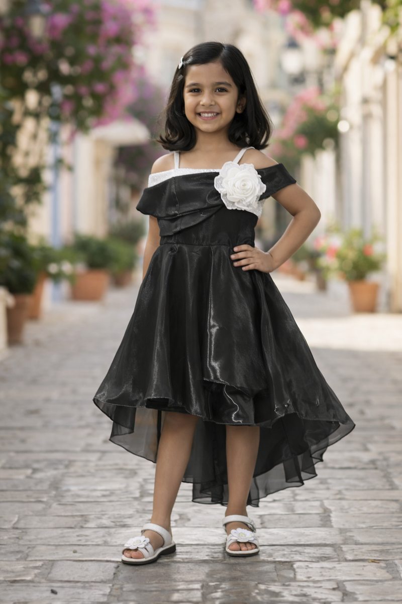Young girl in a black dress with white floral details standing on a stone path.
