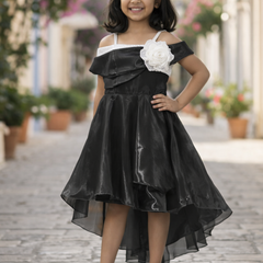 Young girl in a black dress with white floral details standing on a stone path.