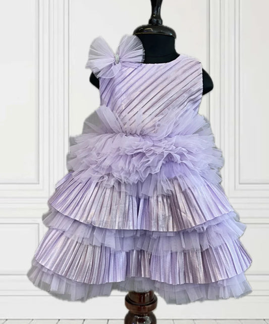  It’s a purple coloured pretty frock with lots of frills and pleated detailing. It features a cute bow detailing on the dress and a back zip closure. 