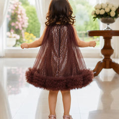 Child wearing a sparkly dress with feathered hem in a bright room.
