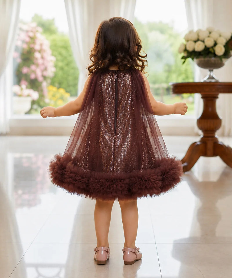 Child wearing a sparkly dress with feathered hem in a bright room.