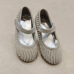 Pair of silver beaded shoes on a beige surface