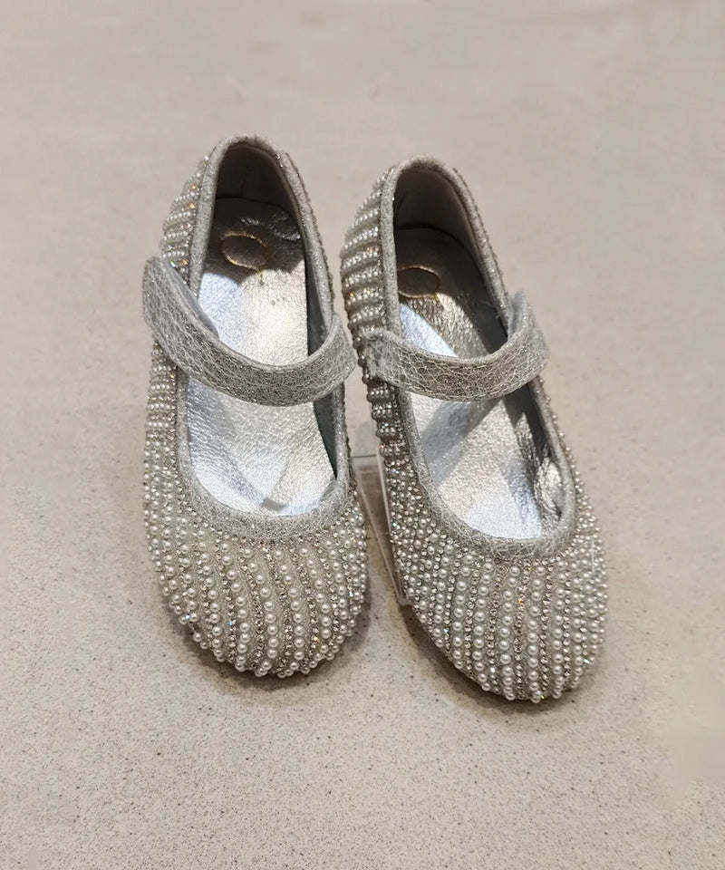 Pair of silver beaded shoes on a beige surface