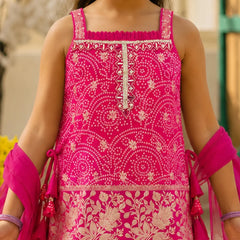 A close-up of a child wearing a bright pink sleeveless embroidered dress with beige floral and geometric patterns, paired with matching pink arm wraps.
