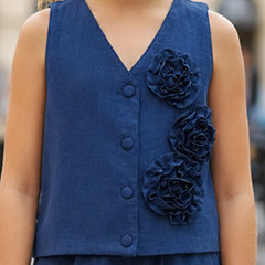 A sleeveless navy blue V-neck vest with three large fabric flowers on the front, worn by a child in an outdoor setting.