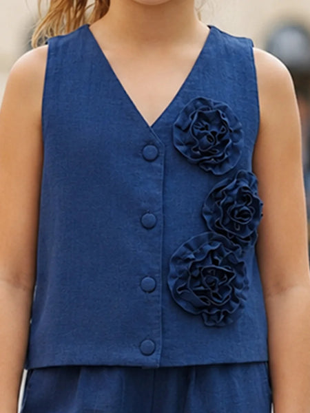 A sleeveless navy blue V-neck vest with three large fabric flowers on the front, worn by a child in an outdoor setting.