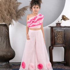 Young girl wearing a pink floral outfit standing in a decorative room.