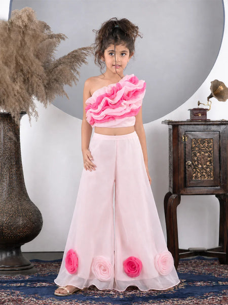 Young girl wearing a pink floral outfit standing in a decorative room.
