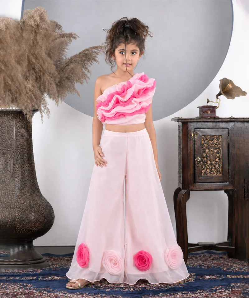 Young girl wearing a pink floral outfit standing in a decorative room.