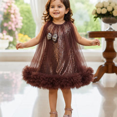 Young girl in a brown sequined dress with a fluffy skirt standing indoors.