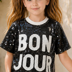 Child wearing a black sequin shirt with 'BON JOUR' text.