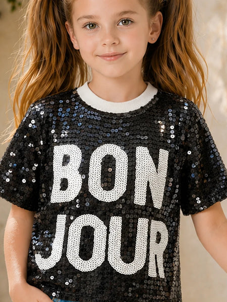 Child wearing a black sequin shirt with 'BON JOUR' text.
