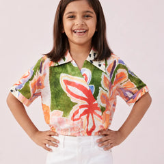 Young girl wearing a colorful floral shirt with a plain background